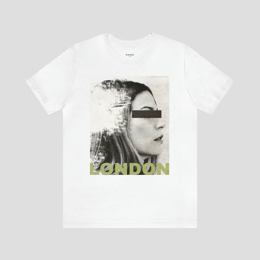 White t-shirt with large, black and white, distressed image of a woman's facial profile. A black bar is over her eyes and the word London is on bottom of image in capitalized light yellow block letters. The shirt image is against a gray background.