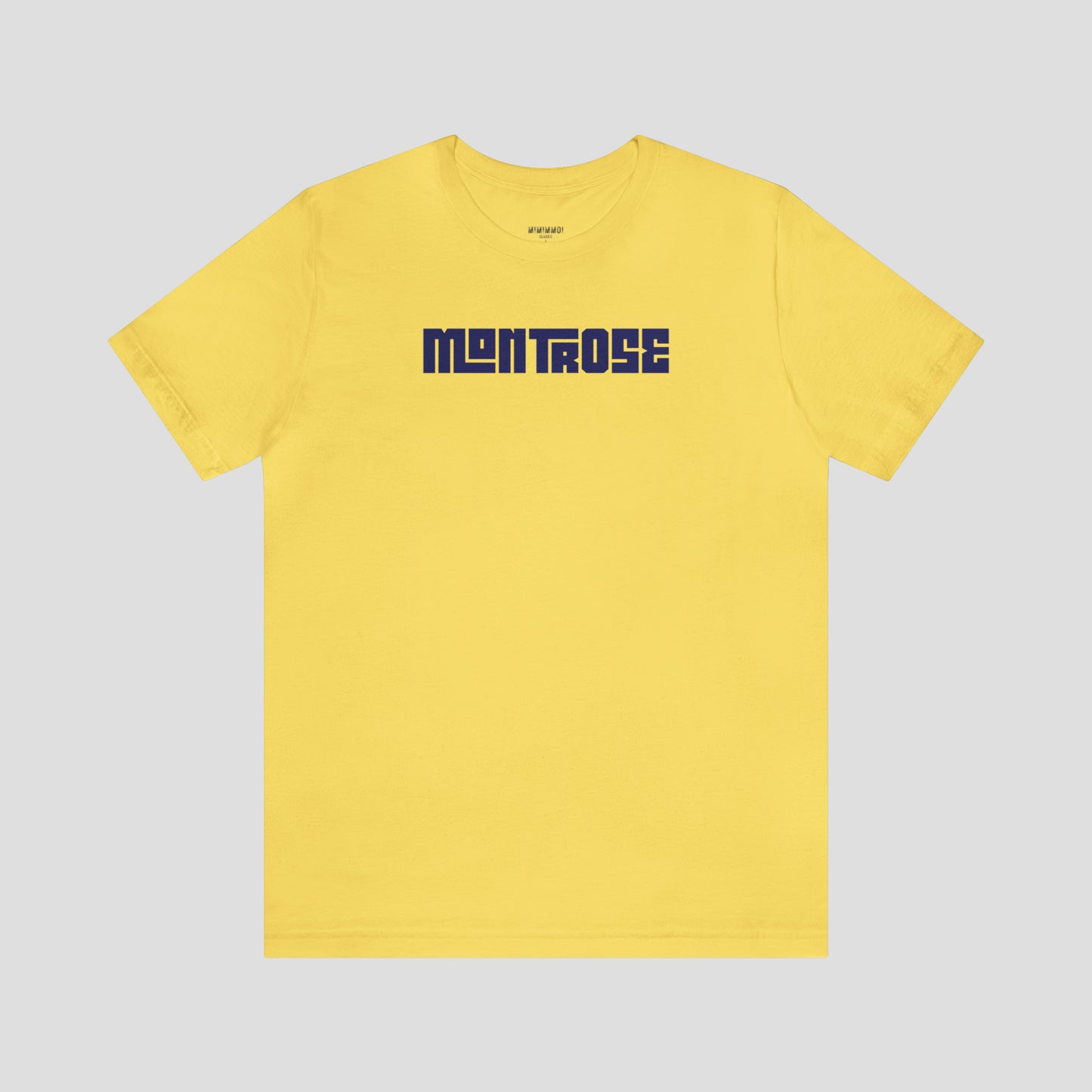 Yellow t-shirt with the word Montrose written in navy colored interlocking block letters across the chest, against a gray background.