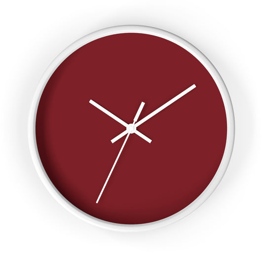 White circular wooden framed clock with dark red background and white hands against a white background.