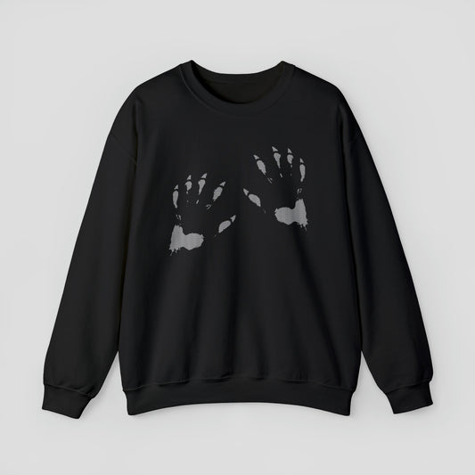 Front view of black sweatshirt with an image of two white werewolf paw prints, against a gray background.