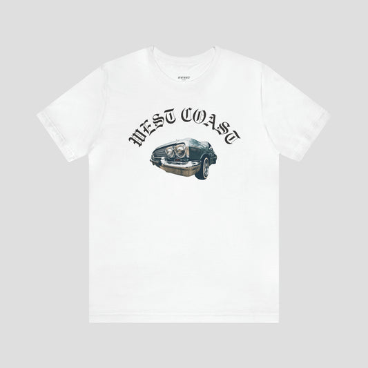 Front view of white t-shirt with image of lowrider car in center with the words "West Coast" curved in a semicircle above in a black, old fashioned font, against a gray background.