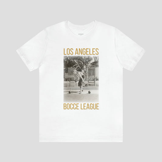 White t-shirt with a retro picture of a female playing bocce ball with the words Los Angeles above and Bocce League below the picture, against a gray background.