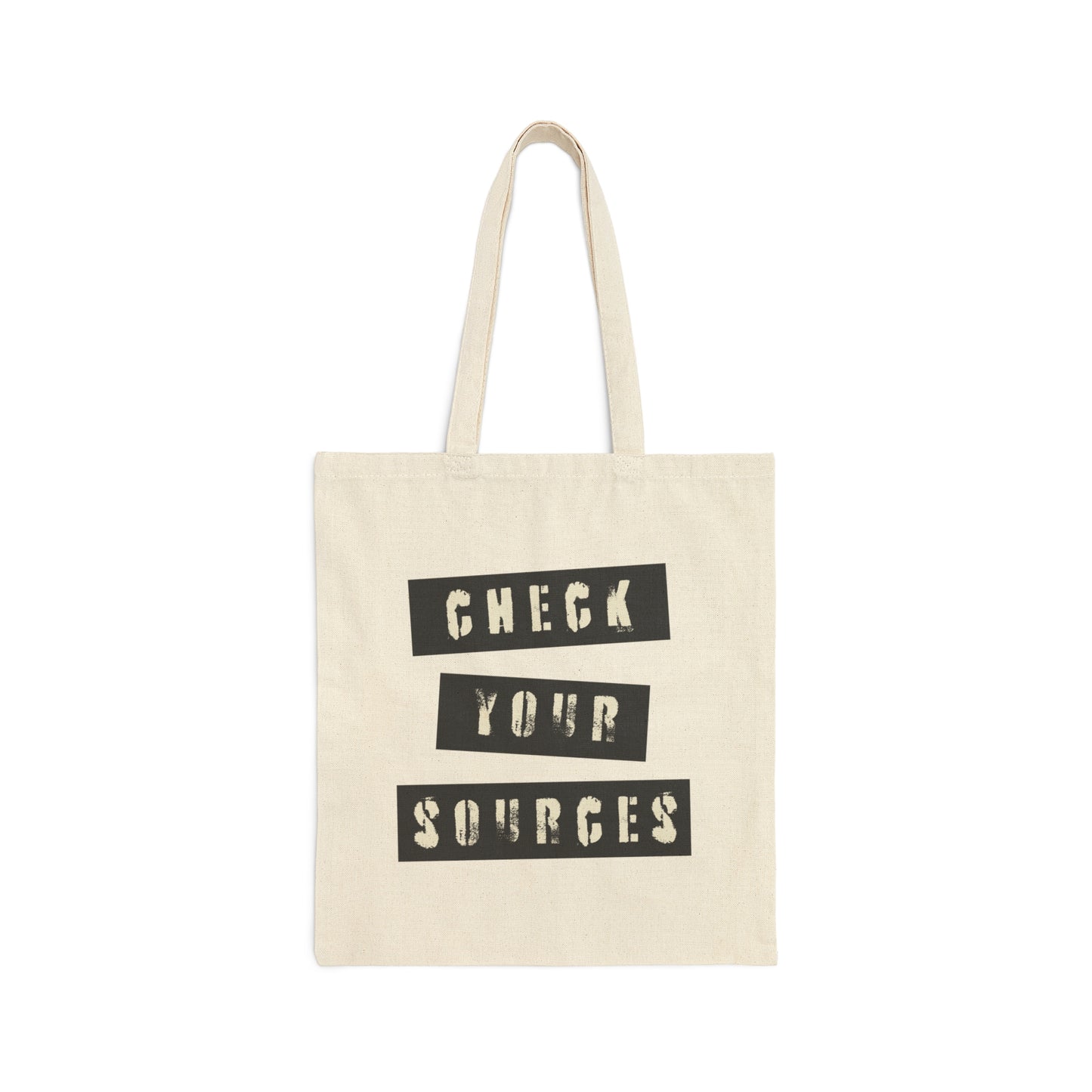 Tan canvas tote bag with "Check Your Sources" written in a grunge font and black boxes with handles above, against a white background.