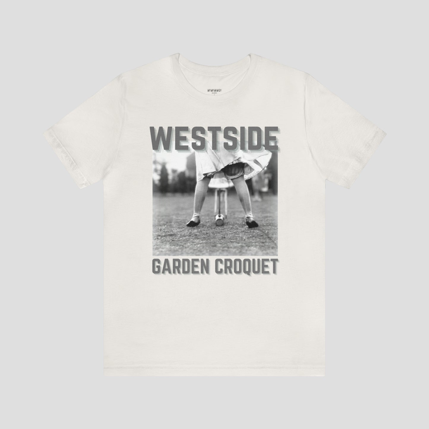 Vintage white t-shirt with gray letters and a vintage photo of person bent over playing croquet against a light gray background.