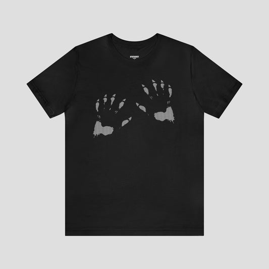 Front view of black t-shirt with an image of two white werewolf paw prints, against a gray background.