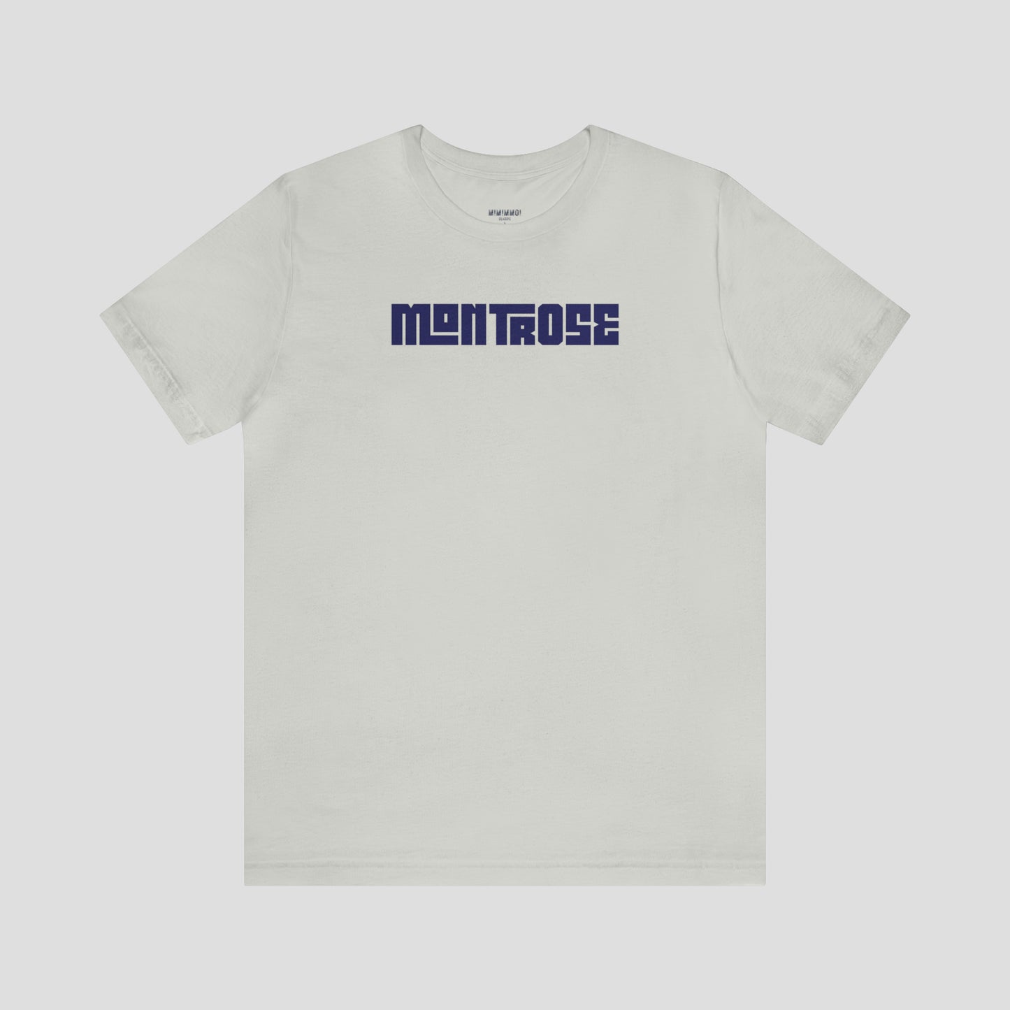 Silver t-shirt with the word Montrose written in navy colored interlocking block letters across the chest, against a gray background.