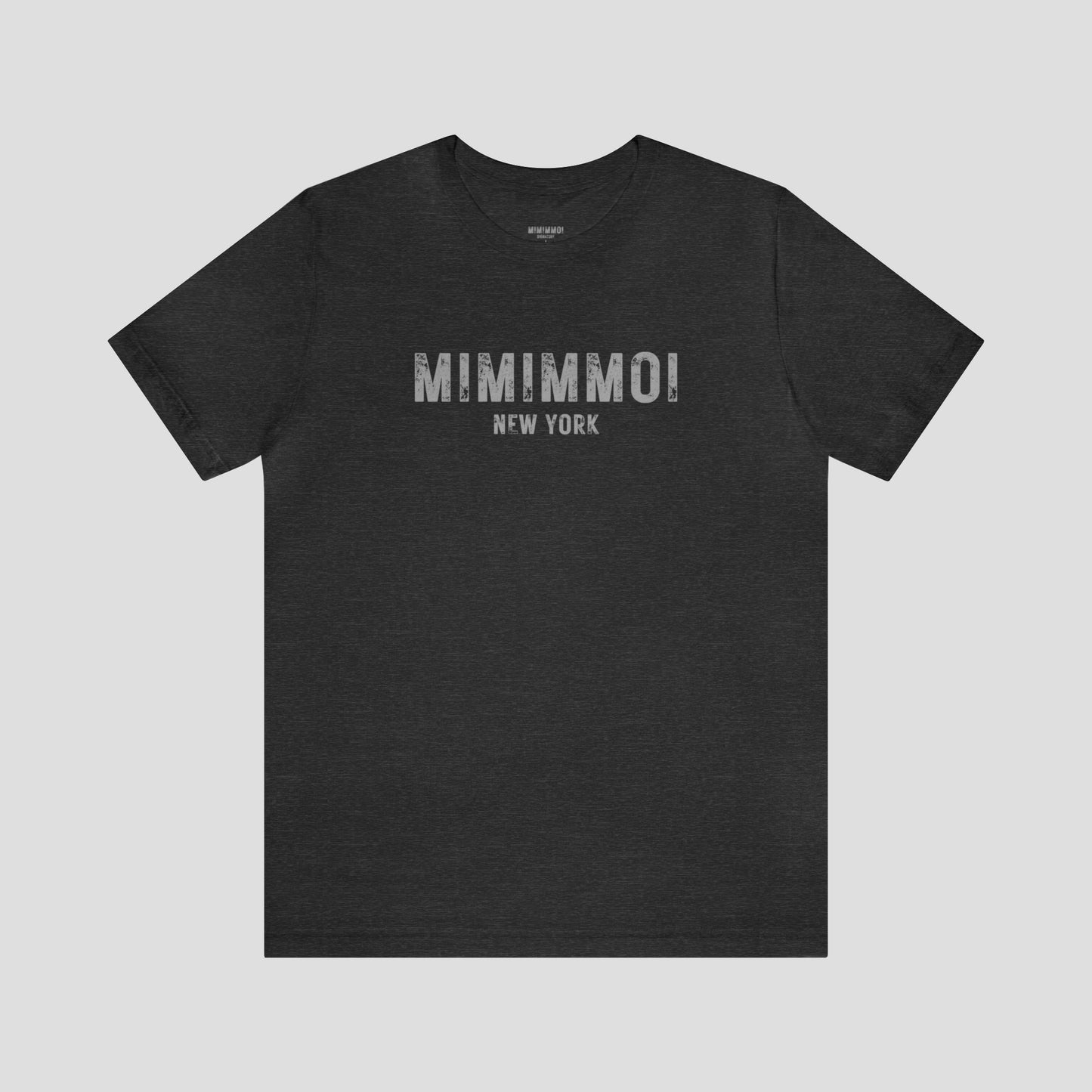 Very dark gray t-shirt with the words Mimimmoi New York in distressed gray block letters across the chest, against a gray background.