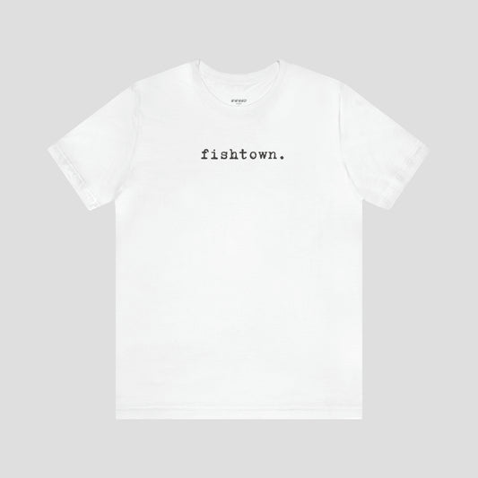 White t-shirt with the word Fishtown written in gray typeface font across the chest, against a gray background.