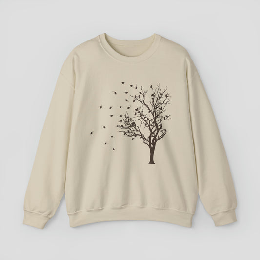 Tan sweatshirt with brown silhouette image of a tree with falling leaves, against a gray background.