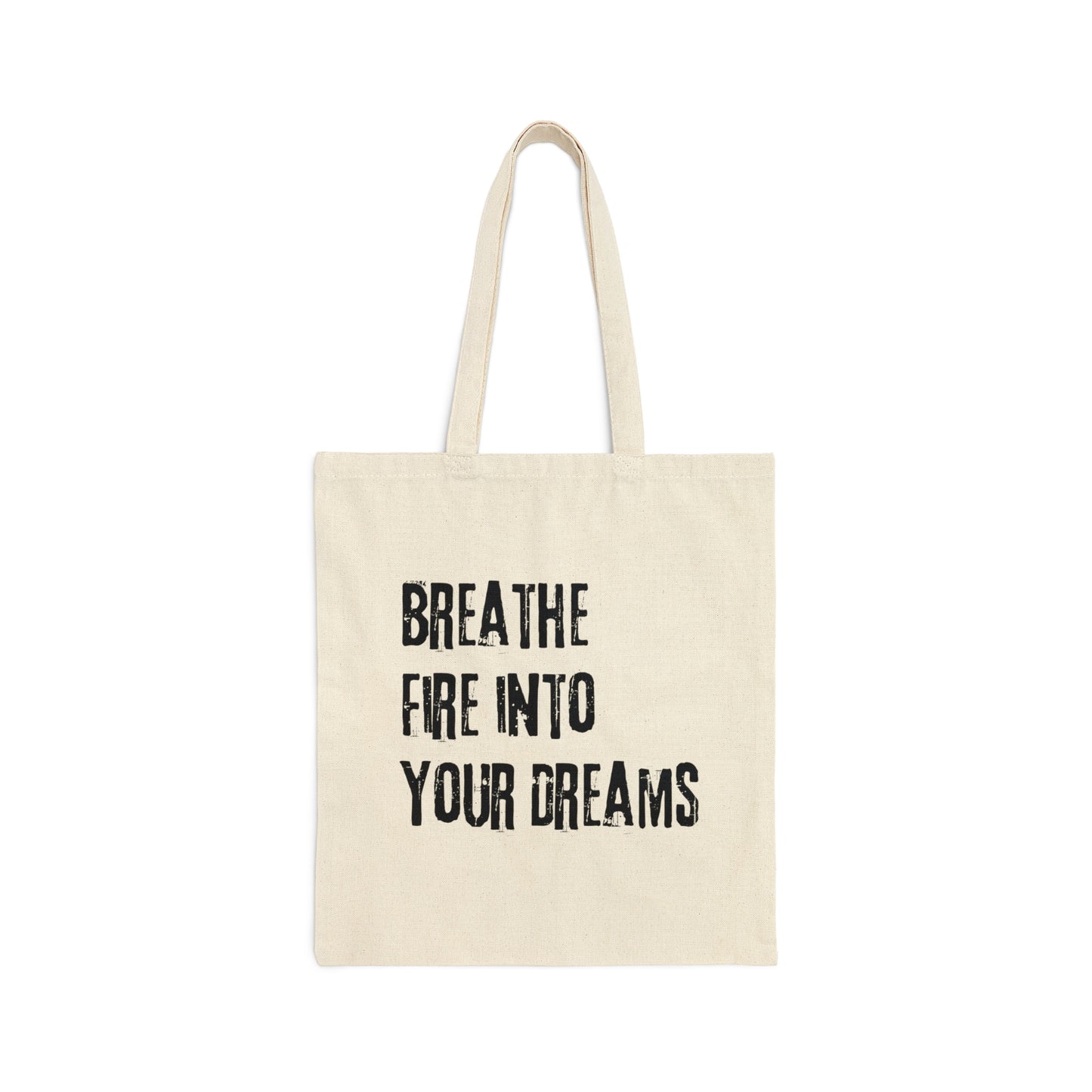 Tan canvas tote bag with "Breathe Fire Into Your Dreams" in a grunge font and handles above, against a white background.