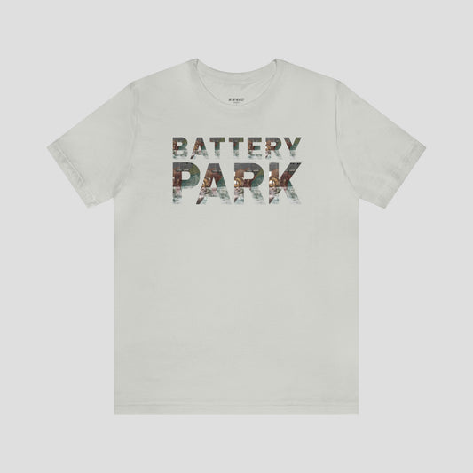 Light silver t-shirt with Battery Park in block letters. A picture of the SeaGlass Carousel is in each block letter against light gray background.