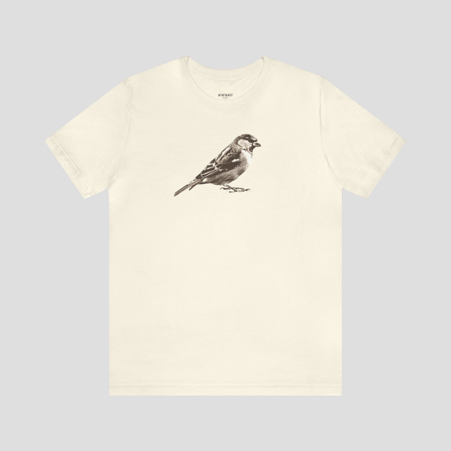 Tan colored t-shirt with large brown and white illustrated image of a sparrow across the chest, against a gray background.